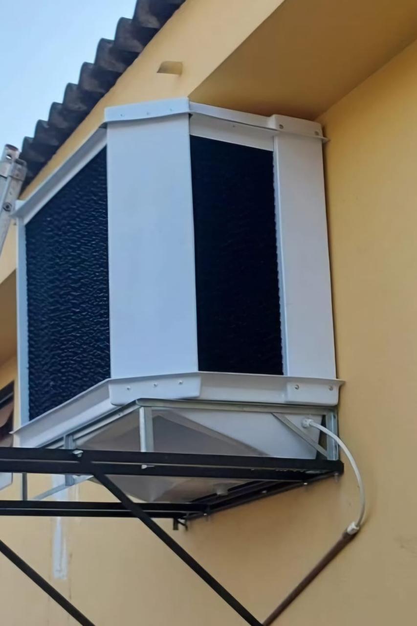 Unidade presa à parede externa, com a saída de ar voltada para uma janela basculante.